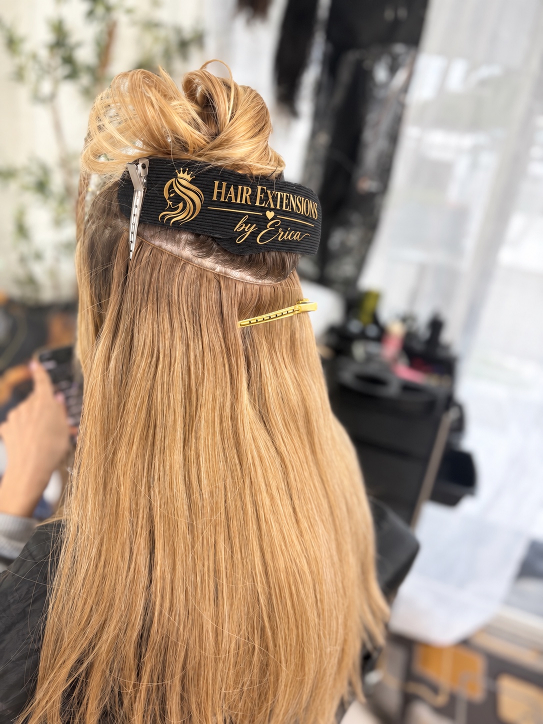 Blonde hair with an installed extension weft and Erica's branded hair gripper
